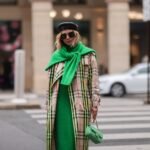 Frau in einem karierten Mantel, grünen Pullover und grünen Schal