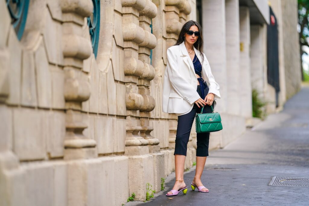 Frau im weißen Blazer und mit einer grünen Handtasche