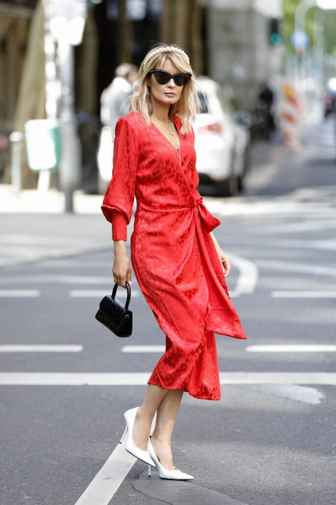 Frau in rotem Kleid, weißen High Heels und mit schwarzer Handtasche