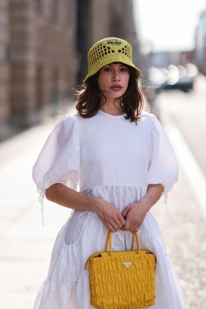 Frau mit gehäkelten Hut von Prada und im weißen Kleid