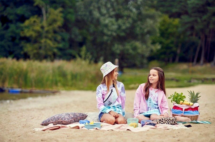 Zwei Mädchen sitzen auf einer Decke am Strand