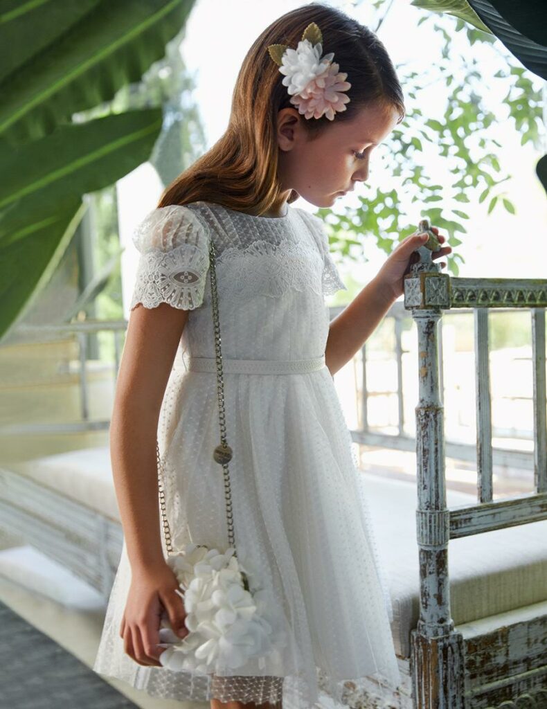 Mädchen im eleganten weißen Kleid und mit einer Blume im Haar