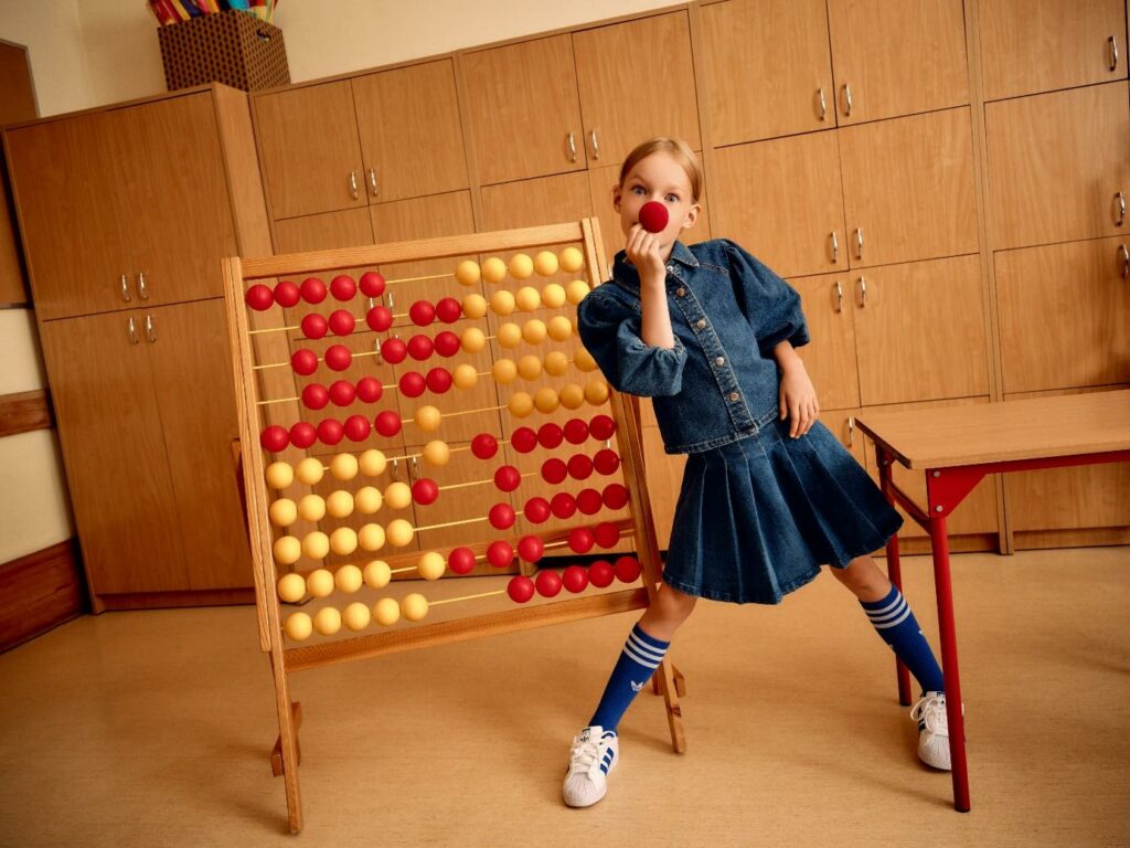 Mädchen im Denim-Look im Klassenraum mit einer roten Clown Nase