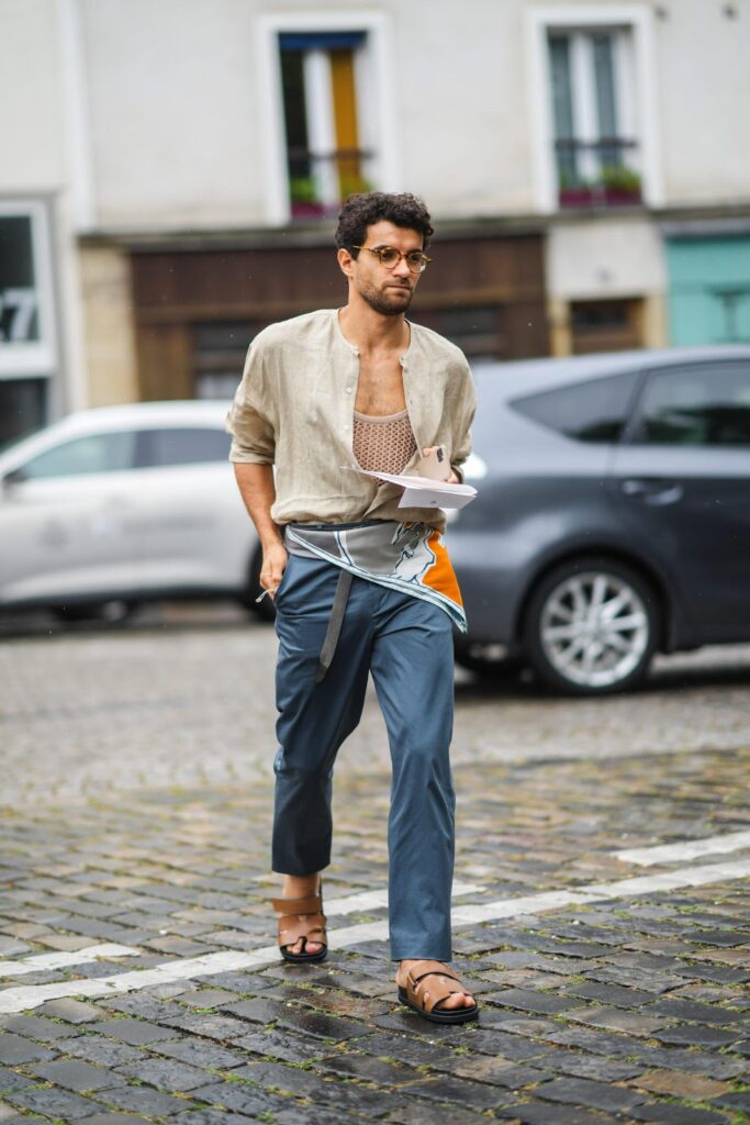 Lässig gekleideter Mann in braunen Pantoletten geht über die Straße