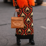 Frau im gemusterten Strickkleid und mit brauner Handtasche von Prada
