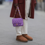 Braune, niedrige UGG Boots, violettfarbene Handtasche, weiße Hose, dunkelroter Mantel