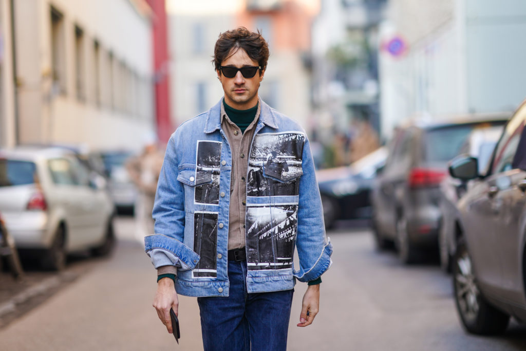 Mann in einer stylischen Jeansjacke geht durch die Straße