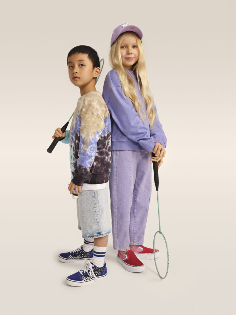 Ein Junge und ein Mädchen in Outfits mit violettfarbenen Elementen in Schuehn von Vans
