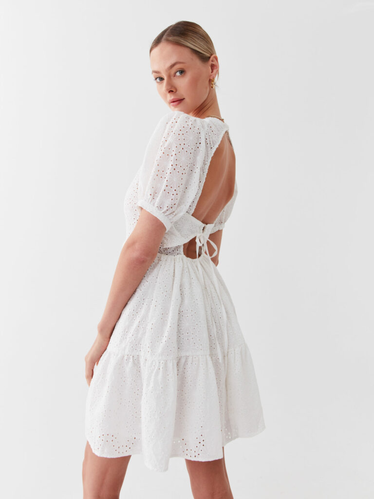 Model in einem weißen Sommerkleid mit Ajourmuster und offenem Rücken