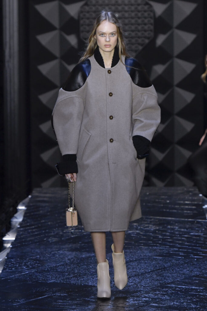 Model in einem grauen Oversize-Mantel mit Ledereinsätzen
