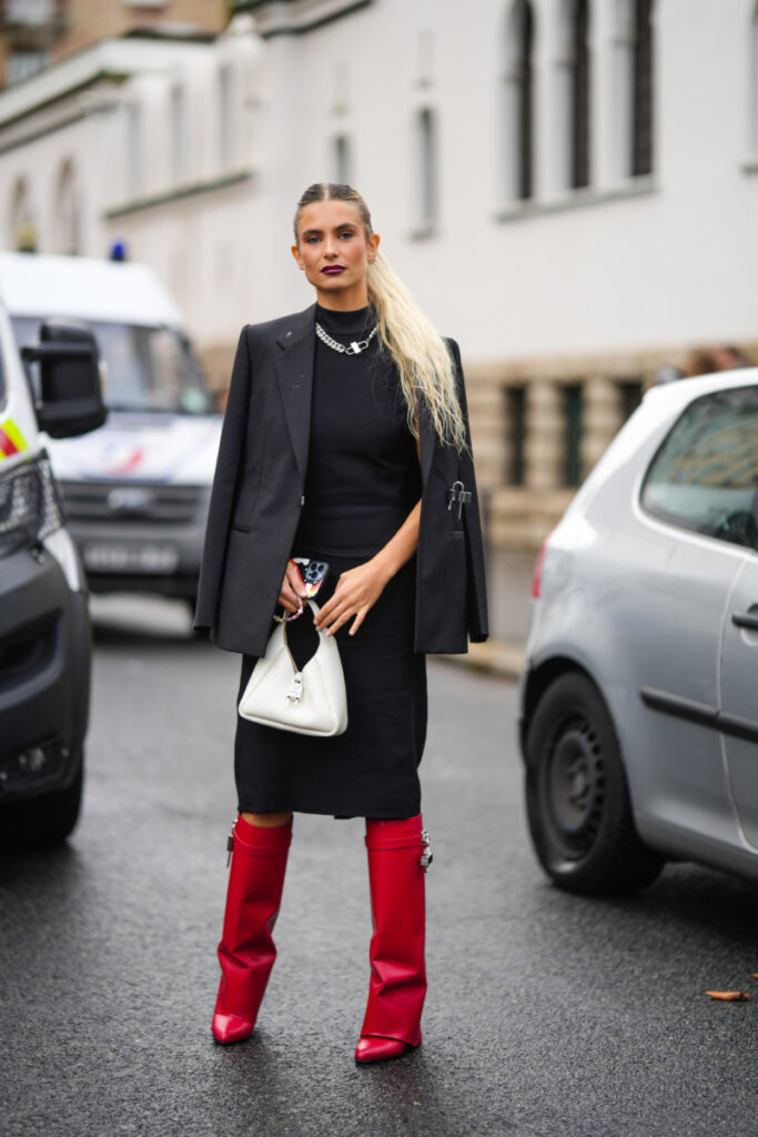 Frau im schwarzen Outfit und in roten Stiefeln