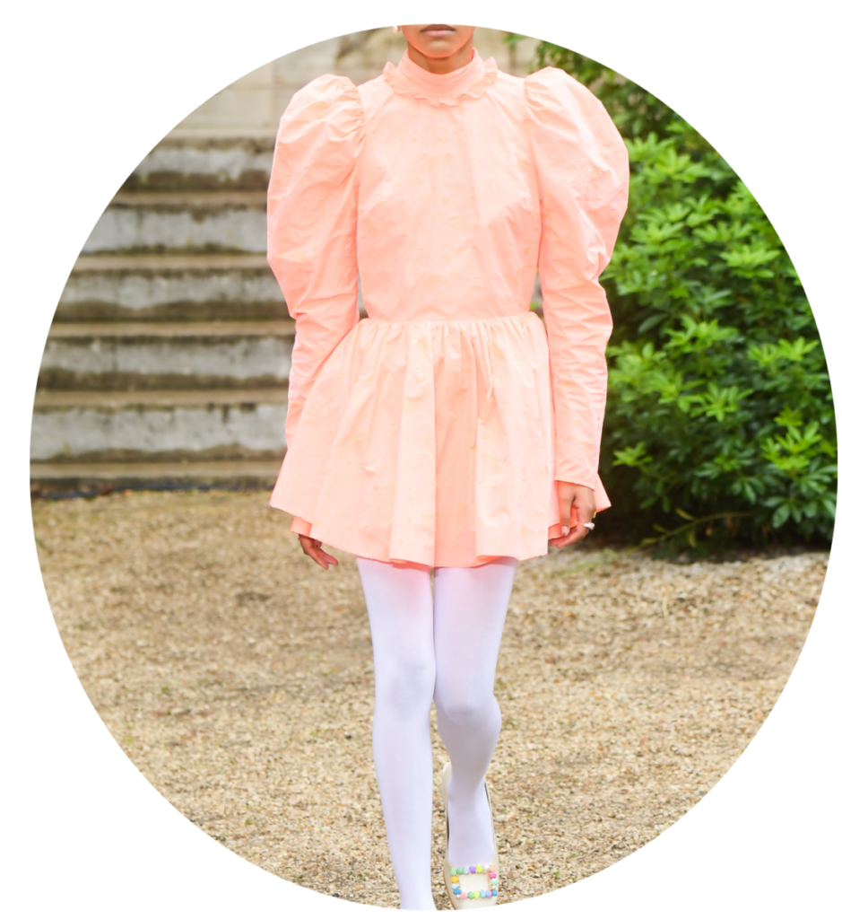 Pantone Farbe des Jahres 2024: pfirsichfarbenes Kleid, weiße Strumpfhosen und Schuhe mit dekorativer bunter Schnalle